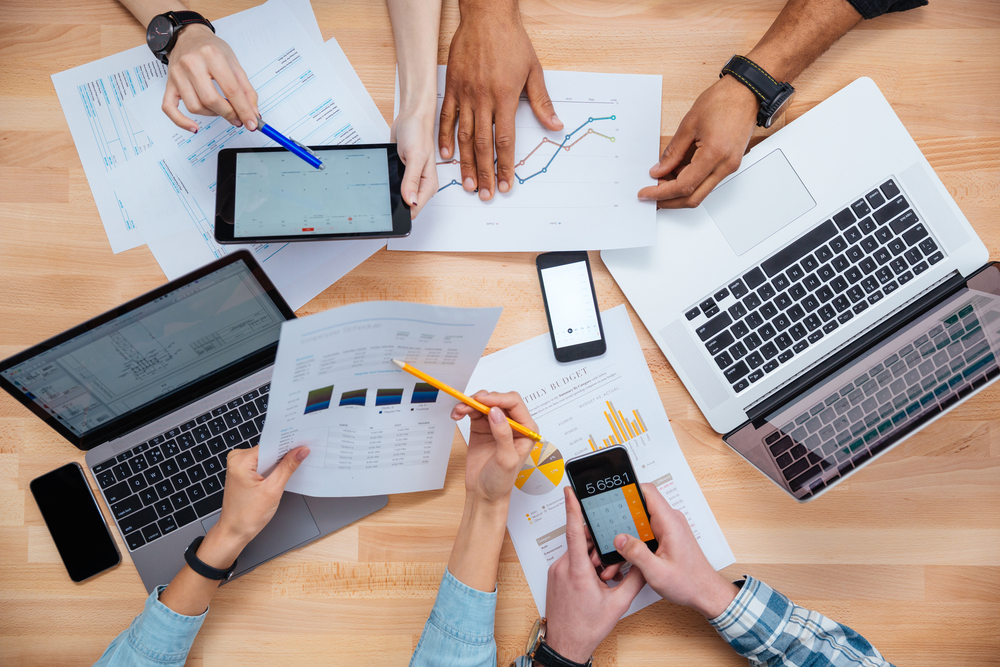 Business people using mobile phones and laptops, calculating and discussing charts and diagrams for financial report Business people using mobile phones and laptops, calculating and discussing charts and diagrams for financial report
